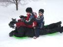The boys riding daddy down the hill.